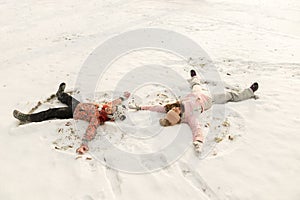 Happy family lying on snow and make angel