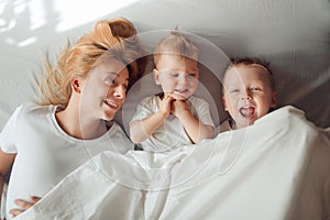 Happy family lying under white blanket in the morning.