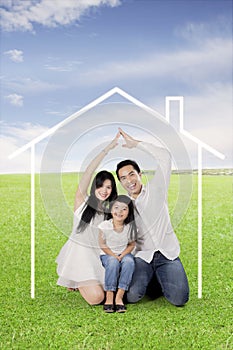 Happy family making hand made house on a meadow