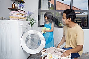 Happy family man father householder and child daughter in laundry with washing machine