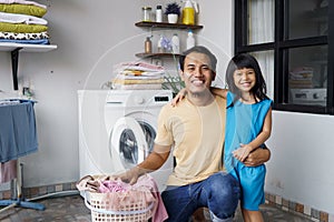 Happy family man father householder and child daughter in laundry with washing machine