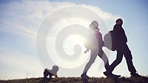 Happy family man and woman teamwork walking go hand in hand silhouette of tourists on top lifestyle of mountain sunlight