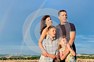 Happy family on a meadow in front of rainbow