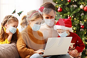 Happy family in medical mask makes a video call on Christmas holiday  in covid 19 coronavirus pandemic