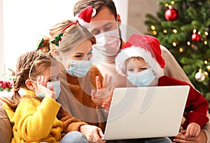 Happy family in medical mask makes a video call on Christmas holiday  in covid 19 coronavirus pandemic