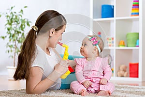 Happy family mom and baby daughter play musical toys