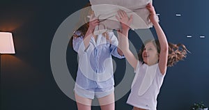 Happy family mom baby sitter and little kid daughter having fun pillow fight on bed, young mother nanny laughing playing