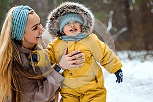 Happy family mom and baby sy on a winter walk in the forest. Concept for christmas, family, relatives, vacations, fresh air