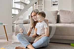 Happy family mom and cute child son holding digital tablet at home.