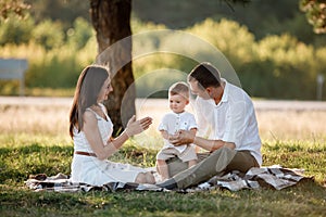 Happy family mom dad and baby son happy in nature spending time together on summer sunny day. The concept of a fun holiday