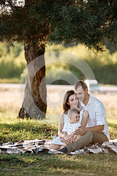 Happy family mom dad and baby son happy in nature spending time together on summer sunny day. The concept of a fun holiday