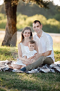 Happy family mom dad and baby son happy in nature spending time together on summer sunny day. The concept of a fun holiday