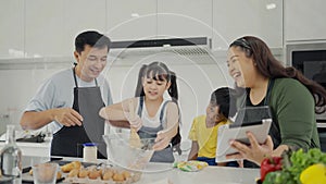 Happy family mom dad and kids siblings cooking together, parents teaching children son daughter cooking fresh vegetable salad and