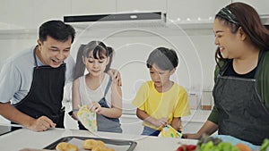 Happy family mom dad and kids siblings cooking together, parents teaching children son daughter cooking fresh vegetable salad and