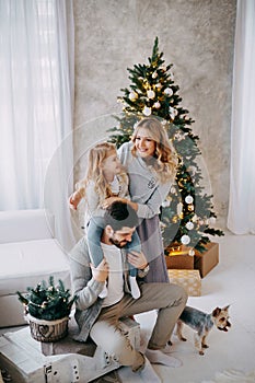 Happy family: mom, dad and pet. Family in a bright New Year& x27;s interior with a Christmas tree