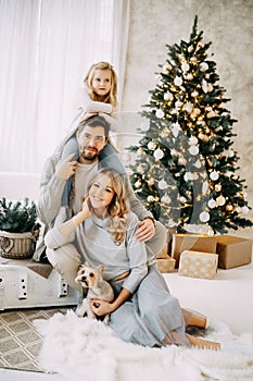 Happy family: mom, dad and pet. Family in a bright New Year& x27;s interior with a Christmas tree