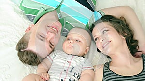 Happy family. Mom dad and six month old baby. Family lying in bed and looking at the camera, smiling.