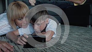 Happy family mom, dad and son watching movies and playing games on phones and laptops