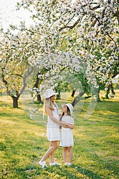 Happy family mom and daughter in a blooming apple orchard in spring