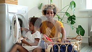 Happy family of mom and daughter are doing household chores in laundry at home.