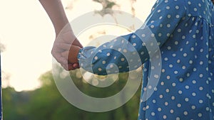 happy family. mom and daughter a hold hands close-up in park. mother and girl kid together hands . parent girl and child