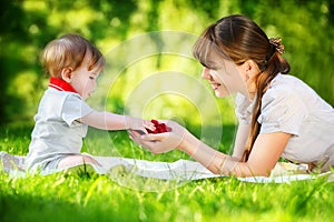 Happy family, mom and little son having fun in the park. Raspberry in his hands. Summer vacations concept.