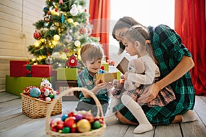 Happy family mom, son and daughter on a Christmas winter sunny morning in a decorated Christmas celebration room with a