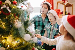 Happy family mom, son and daughter on a Christmas winter sunny morning in a decorated Christmas celebration room with a