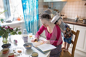 Happy family mom and son at home kitchen together read book