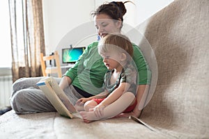 Happy family mom and son at home kitchen together read book