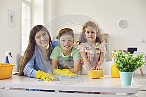 Happy family with mom and two children cleaning up at home. Parent and kids doing domestic chores together indoors