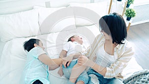 Happy family mom and two sons playing and having fun on the bed.