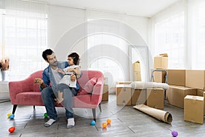 Happy family moment in the house. Father and daughter relaxing on red sofa. The family just moving in new house