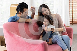 Happy family moment in the house. Father mother and daughter relaxing on red sofa. The family just moving in new house