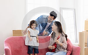 Happy family moment in the house. Father mother and daughter relaxing on red sofa. The family just moving in new house