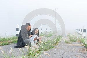 happy family in morning with cold weather and fog covering area, father mother take their cute little daughter come see fog feel