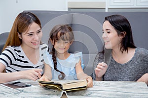 happy family mother, aunt, freind and daughter teaching read a book.