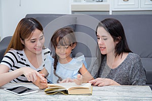 Happy family mother, aunt, freind and daughter teaching read a book at home.