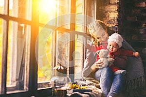 Happy family mother and baby in autumn window