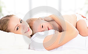 Happy family mother and baby in bed