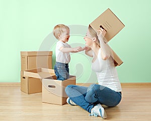 Happy family mother and baby daughter in an empty apartment with cardboard boxes