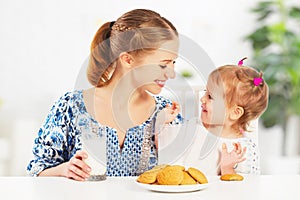 Happy family mother and baby daughter girl at breakfast: biscuit