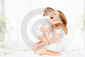 Happy family mother and baby daughter playing and laughing baby