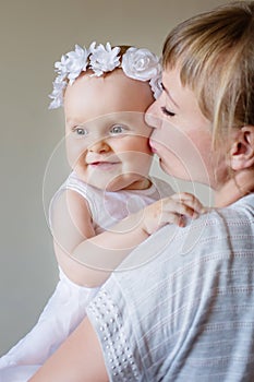 Mother and baby daughter plays, hugging, kissing at hom