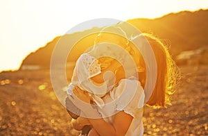 Happy family. Mother and baby girl daughter on beach at sunset