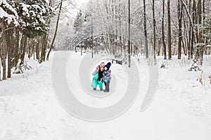 Happy family mother and baby girl daughter playing and laughing in winter outdoors in the snow