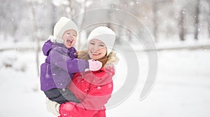 Happy family mother and baby girl daughter playing and laughing in winter snow