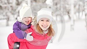Happy family mother and baby girl daughter playing and laughing in winter snow