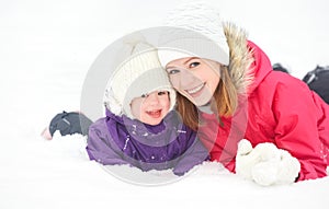 Happy family mother and baby girl daughter playing and laughing in winter snow