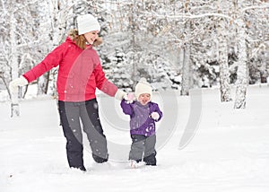 Happy family mother and baby girl daughter run, walk and playing in winter snow